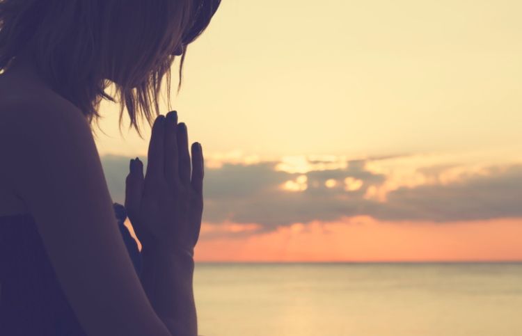 Woman praying at sunrise