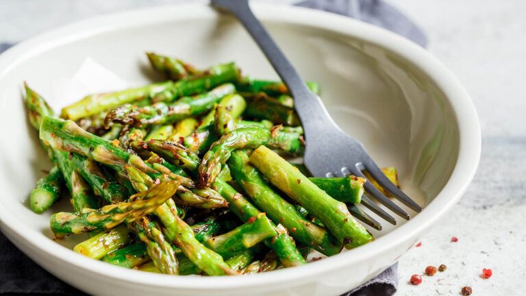 Cooked spring asparagus in a white bowl