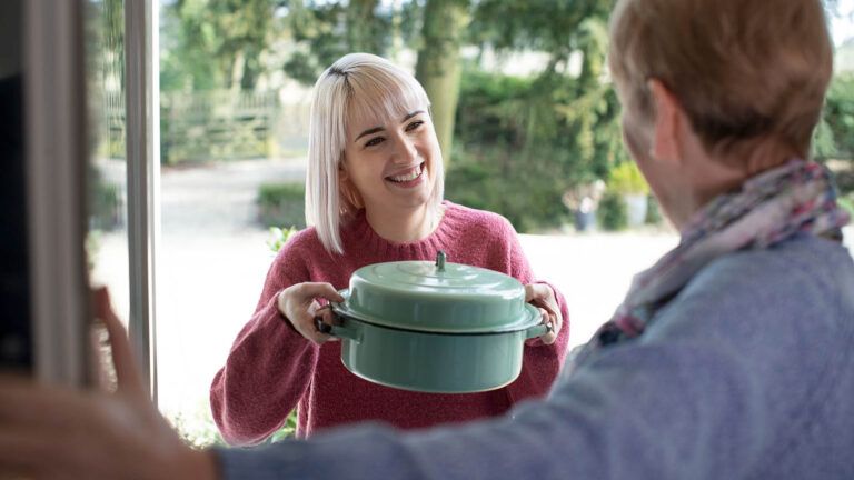 Woman doing an Easter act of kindness by bringing her elderly neighbor a meal