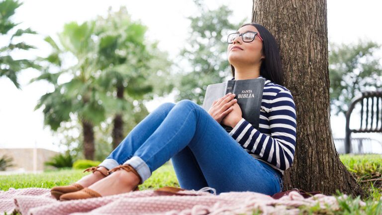 Woman praying outside with her Bible as her easter act of kindness