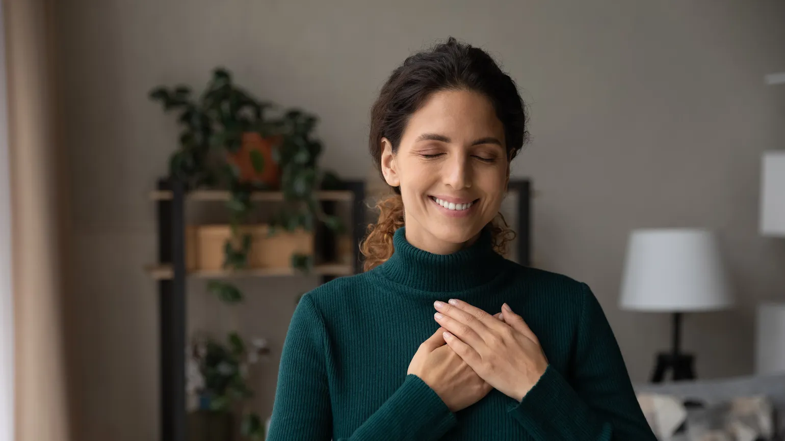 Woman in her living room with her hands on her heart feeling God's love through quotes