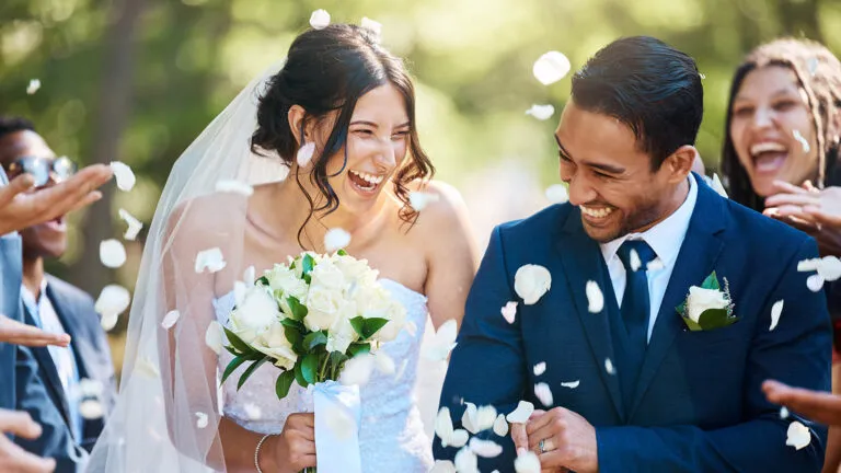 Guests throw rose petals at a couple at their wedding