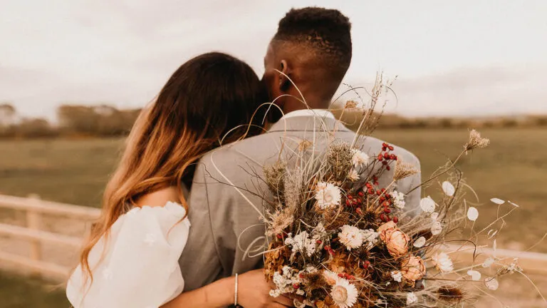 The back of a couple holding each other outside at their wedding