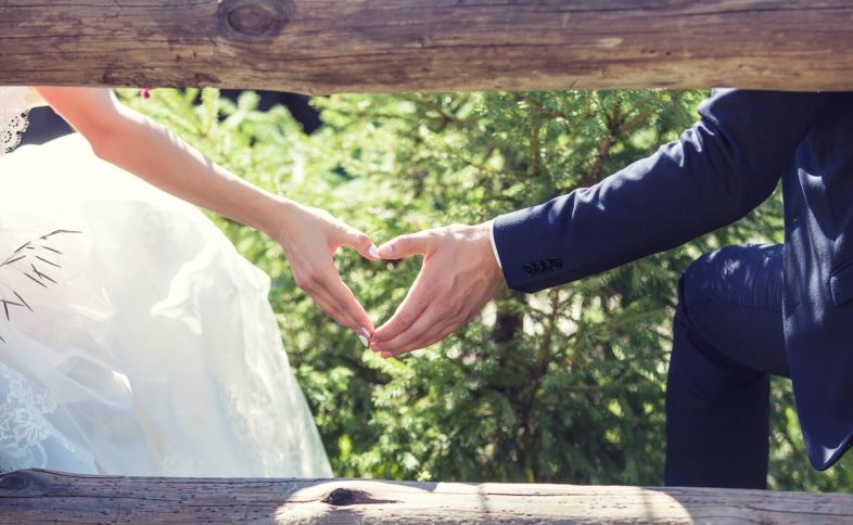 A married couple makes a heart with their hands as their wedding blessing