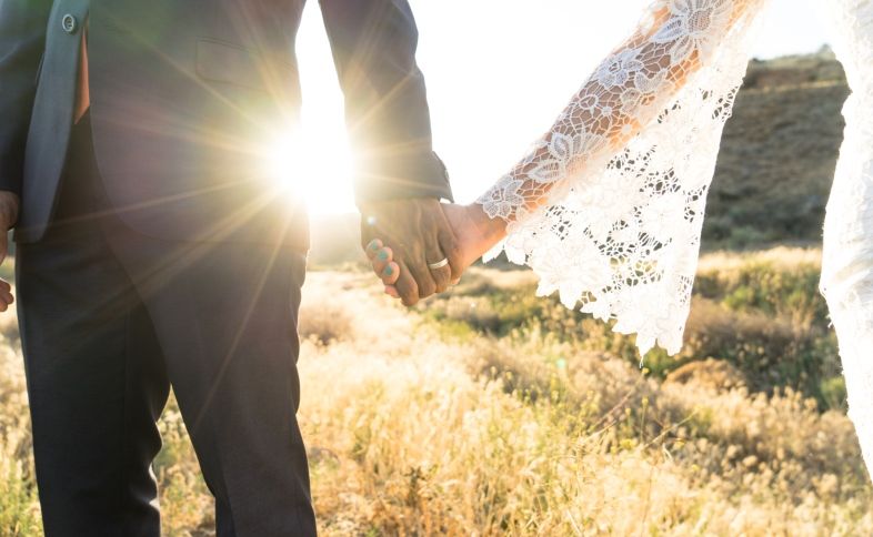 a bride and groom hold hands at sunset after hearing wedding blessings