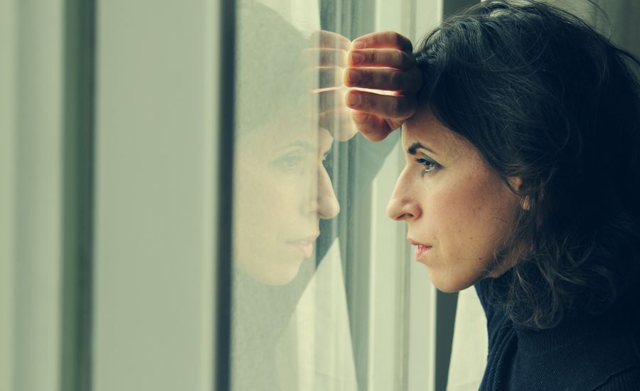 A troubled woman gazes through a window