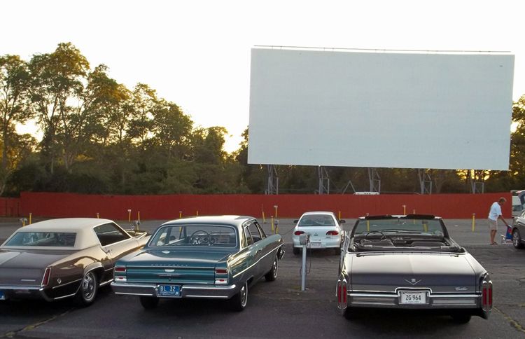 Three classic cars parked in the lot at Cape Cod's Wellfleet Drive-in