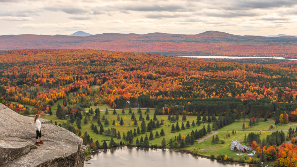 Woman looking at Lyster lake with forest of Quebec and Vermont seen from the Mount Pinacle in Coaticook during autumn. Woman looking at lake and forest during autumn.
