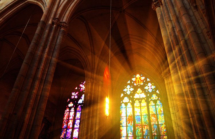 Sunlight streams through a church's stained glass windows