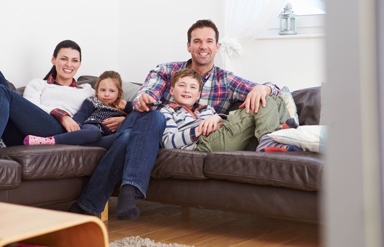 A family relaxes on the couch watching television together
