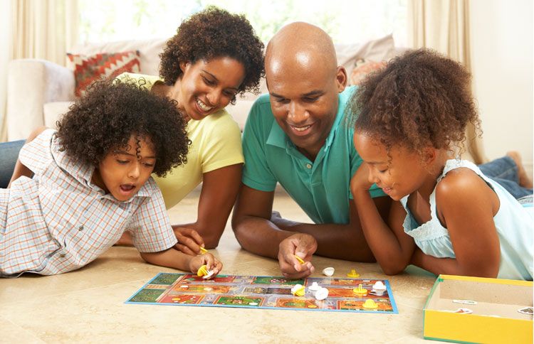 A smiling family is gathered around a board game
