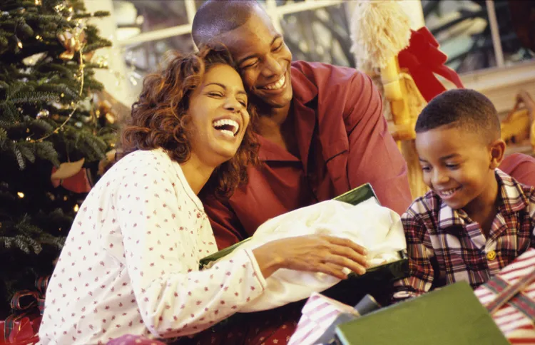 The members of a loving family smile as they open their Christmas presents