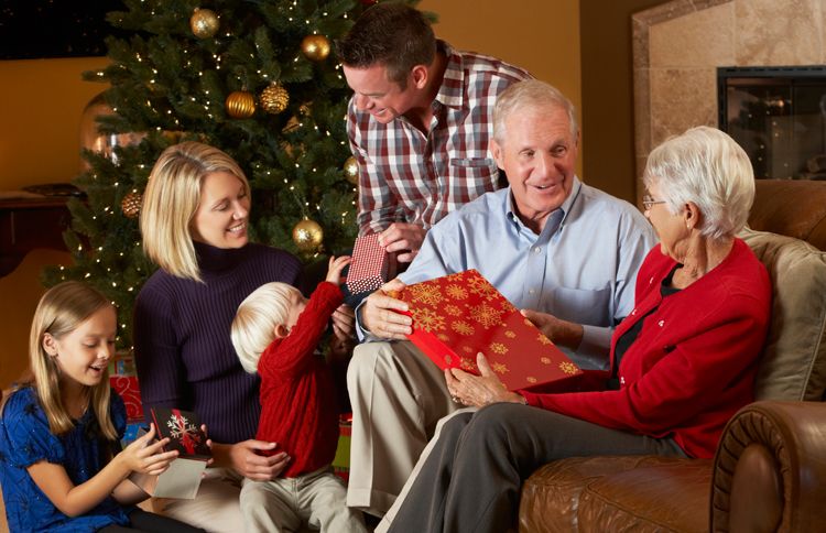 Children, parents and grandparents exchange gifts under a Christmas tree