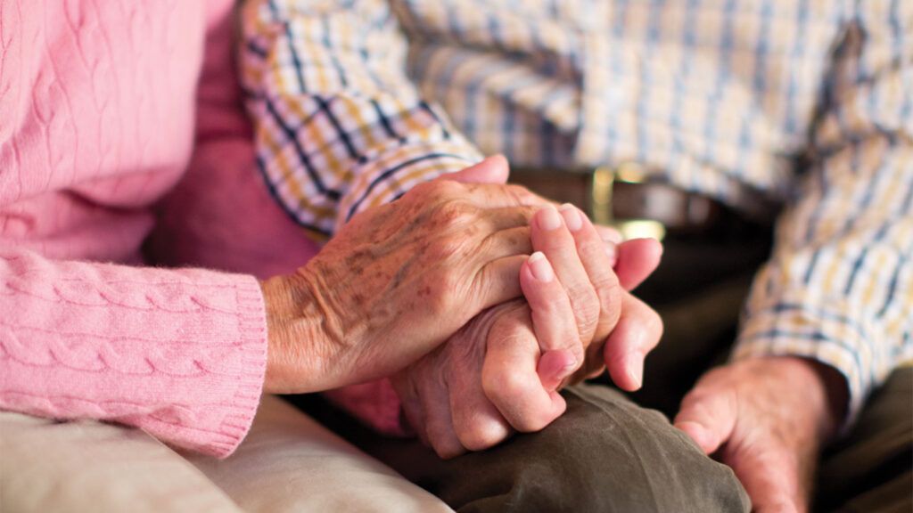 A senior couple holds hands