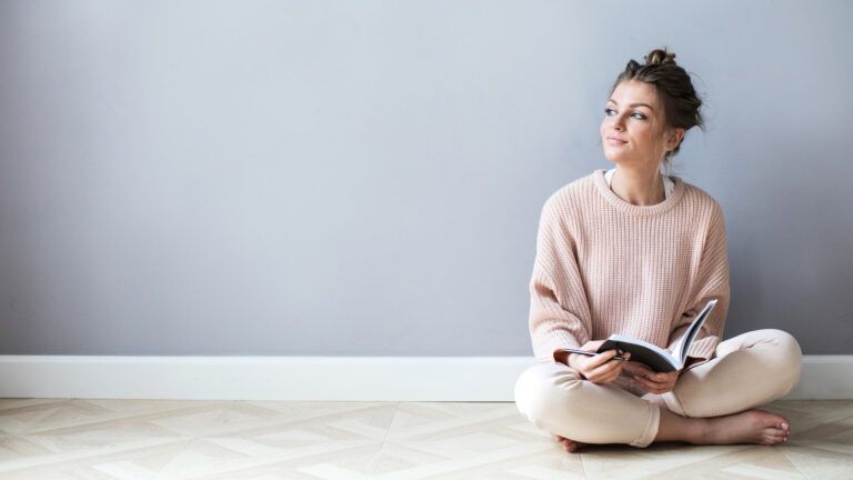 Woman sitting on the floor writing about her spiritual spring cleaning