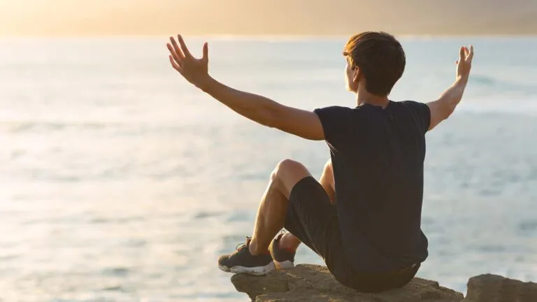 Man outside with his arms up saying his holy week prayers