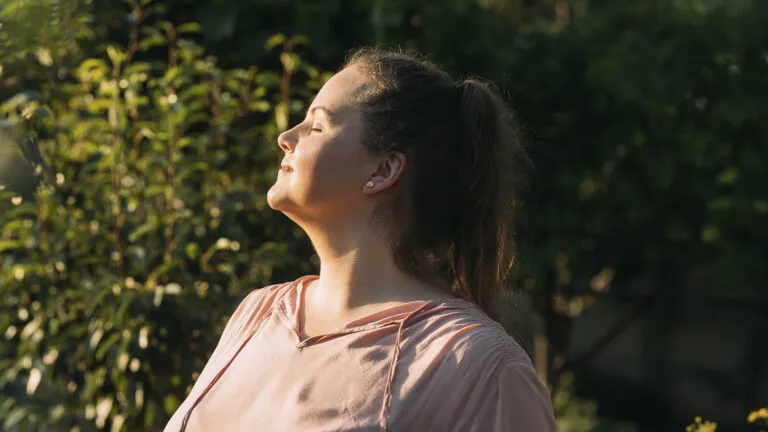 Woman saying her holy week prayers with her eyes closed in a garden