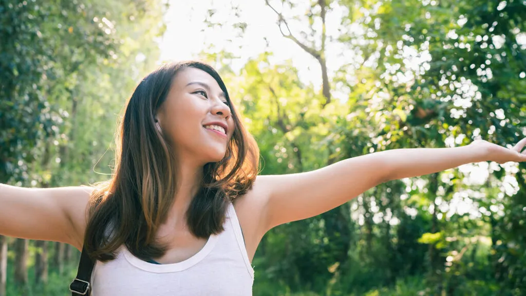 Woman with her arms up in the woods saying her holy week prayers