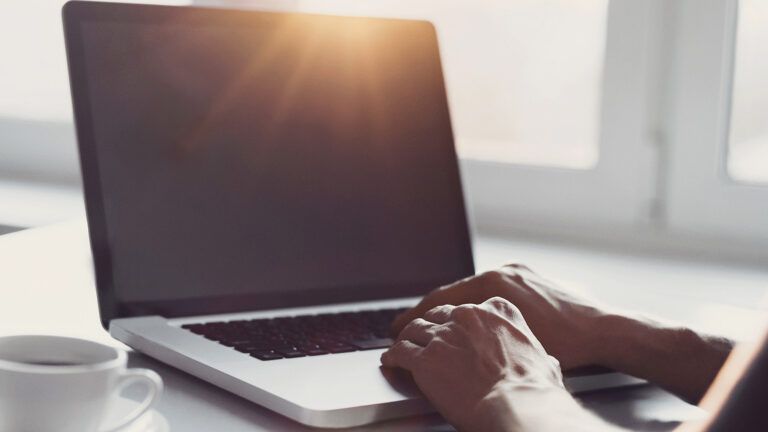 A woman types a comment on her laptop computer.