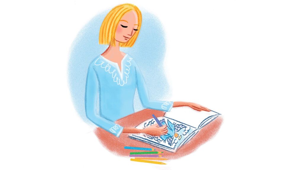 A young woman smiles serenely as she colors in a coloring book