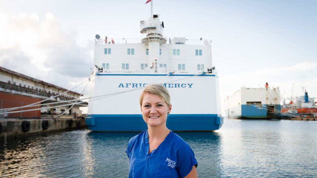 Heather Morehouse poses in front of the ship she served on, Africa Mercy