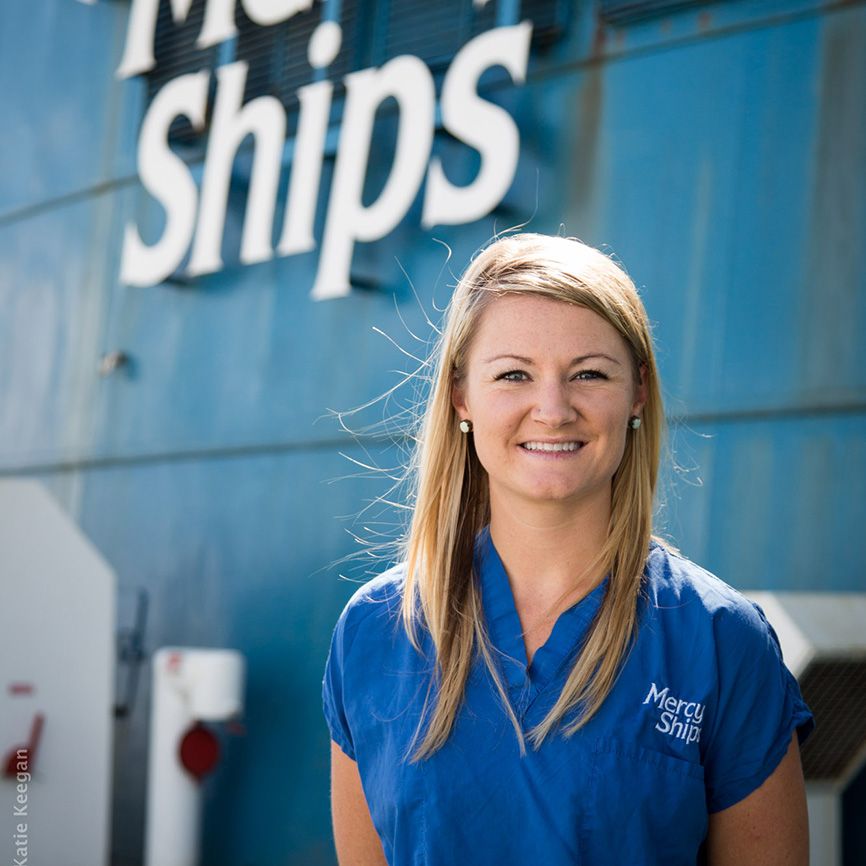 Heather poses in front of a Mercy Ships vessel