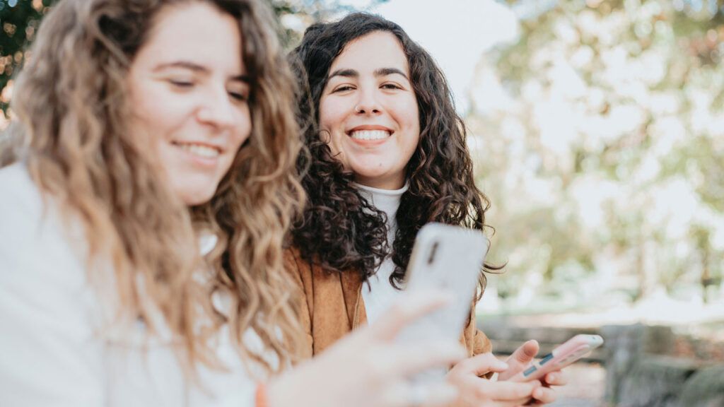 Two women looking at their cellphones.