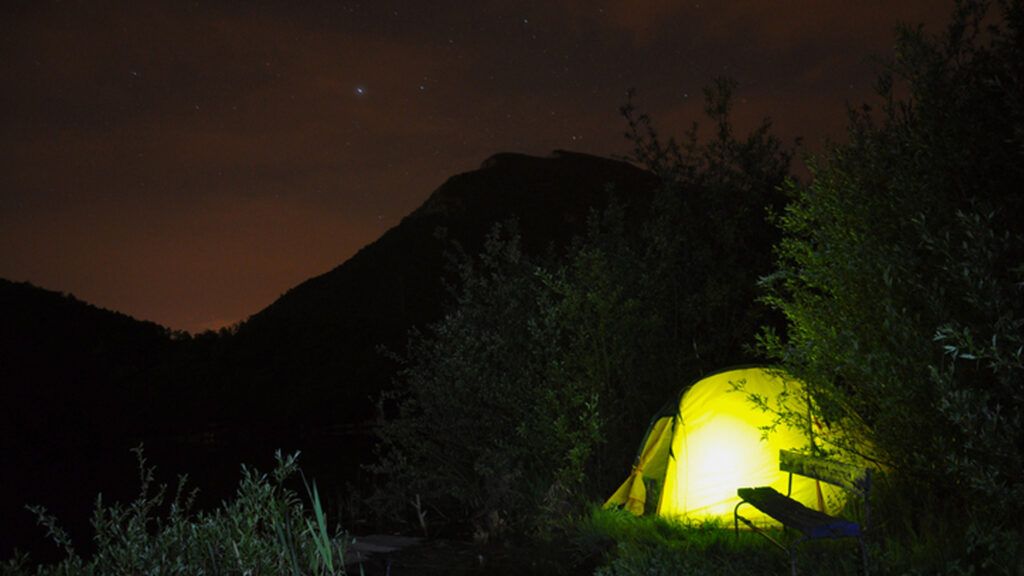 Mountainous landscape with illuminated camping tent