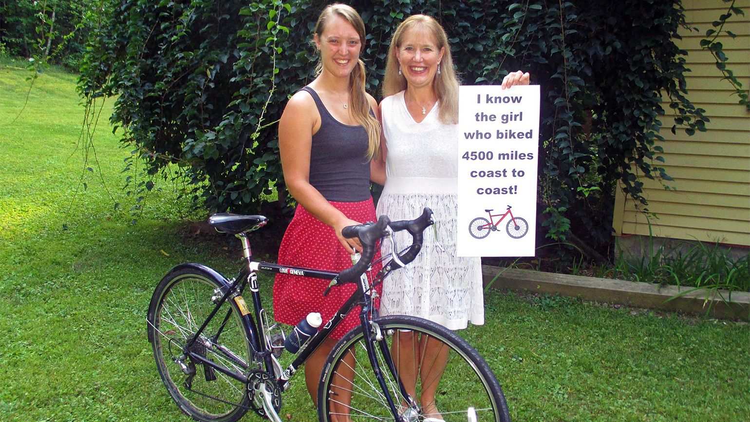 Proud mom Merry Lee poses with a sign celebrating her daughter Deborah's accomplishments in completing the memorable cross-country bike trek.