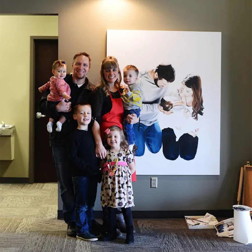 Jessie poses by her work-in-progress with her husband and children