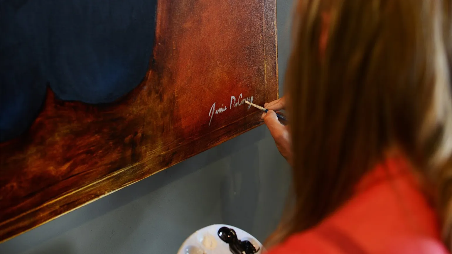 Jessie signs her name to the completed painting