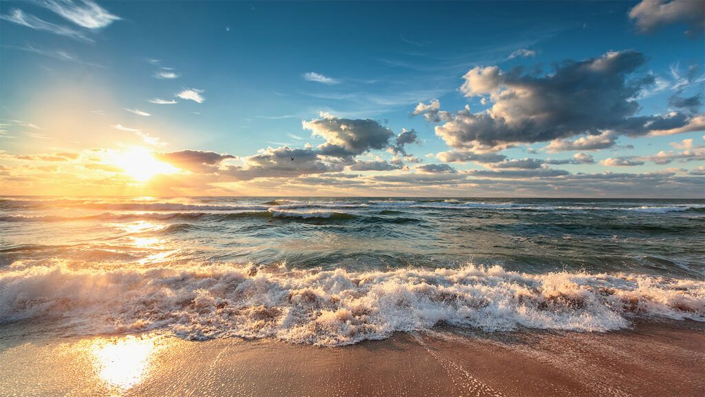 sunrise over the ocean waves on a beach, summer solstice