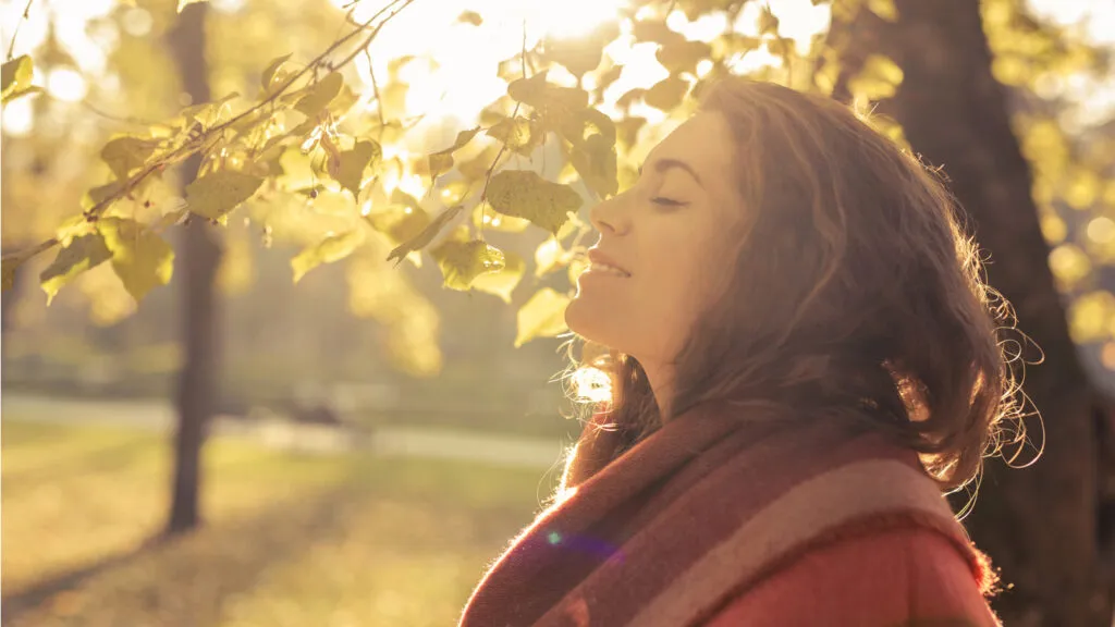 A relaxed woman outside on a bright Fall day.