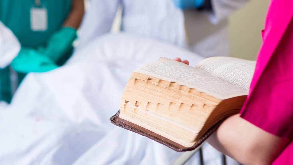 A young nurse reads the Bible for a patient