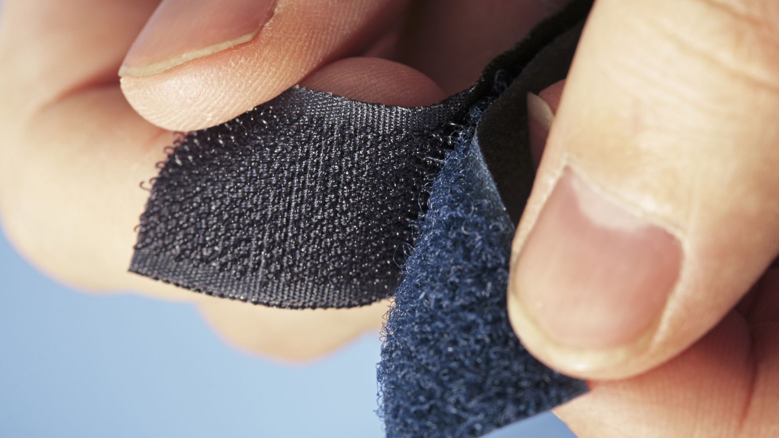 A person tearing a piece of Velcro apart.
