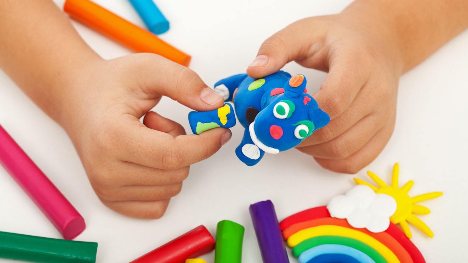 A child's hands building an animal with blue Play-Doh.