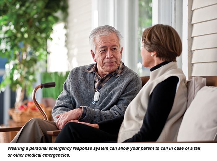 A pair of seniors converse on a porch; the man wears personal emergency device around his neck