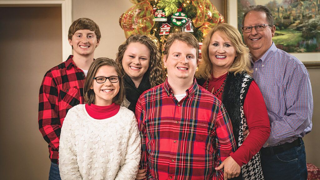 A family family in Christmas sweaters offers their Christmas pageant script