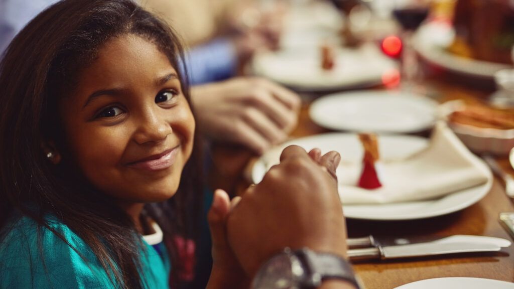 A young girl at the dinner table with attributes of gratitude