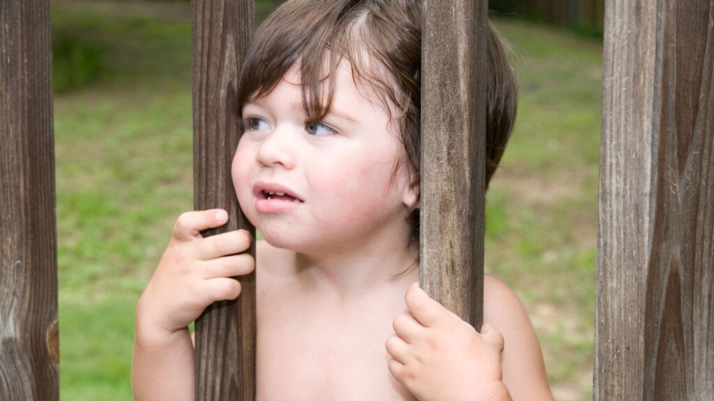 Child stuck behind fence.