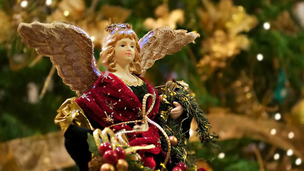 An ornament of an angel in a Christmas tree wearing festive holiday robes