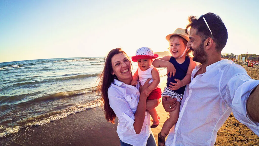 A happy family having a lot fun at the beach while taking pictures.