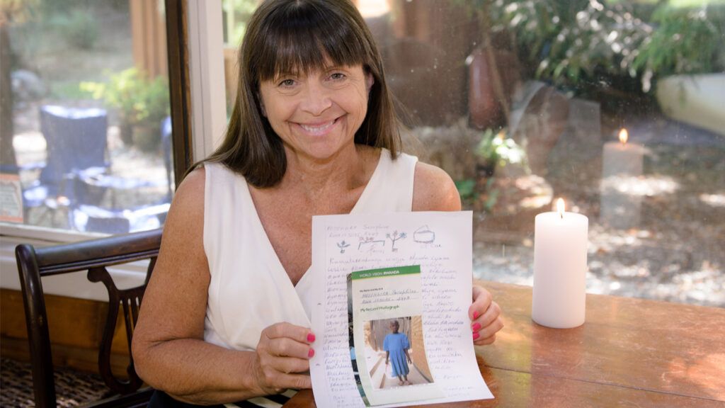 Leslie Kelly holds a letter she received from her sponsored child, Seraphine.