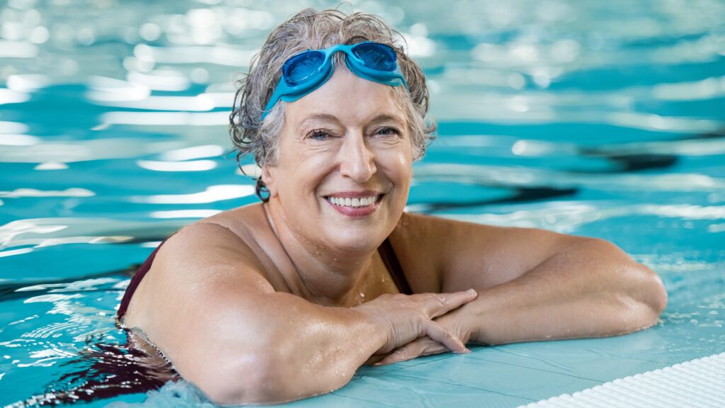 A senior citizen woman enjoying herself in the pool.