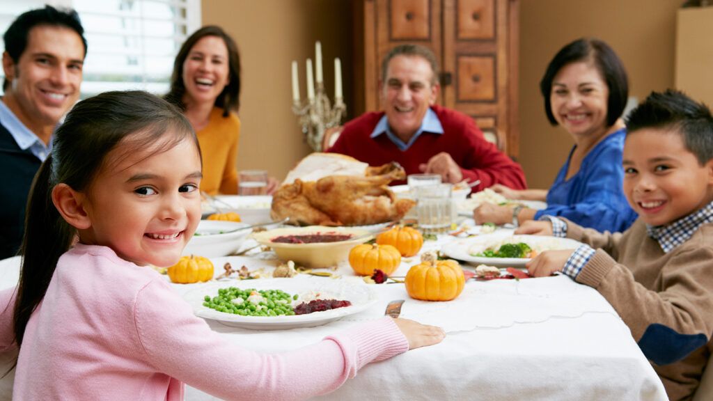 A smiling family surround a dining table with no Thanksgiving stress