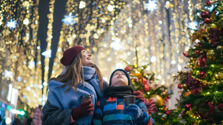 A mother and son looking up at Christmas lights with hopeful expressions