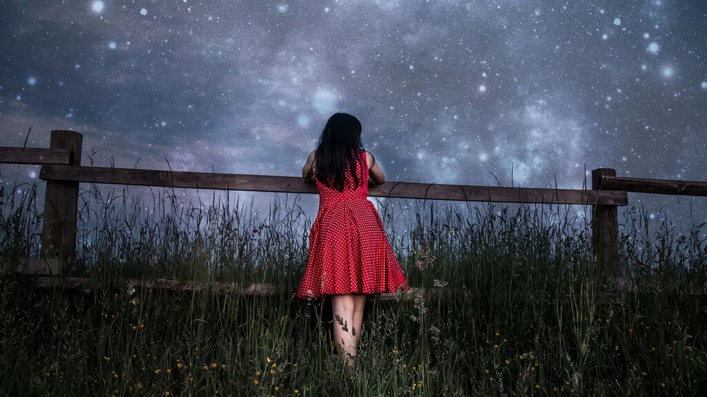 A young girl gazes up at a star-filled sky