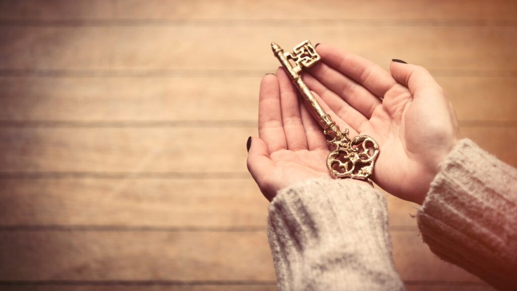 A woman's hands holding a golden key.