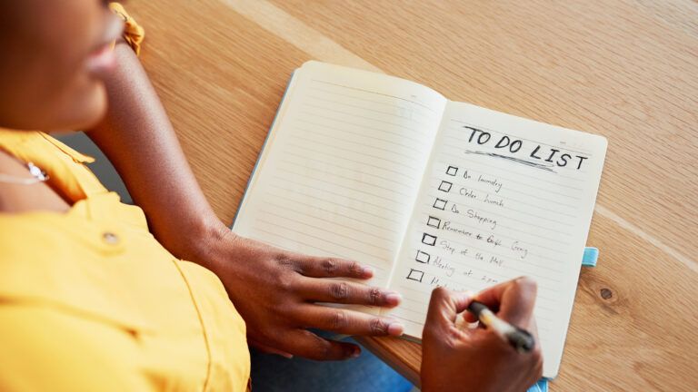 Woman in a yellow shirt writing a to do list of her new year habits