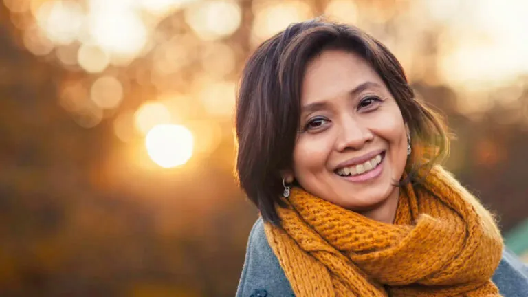 A woman smiles on a sunny autumn day